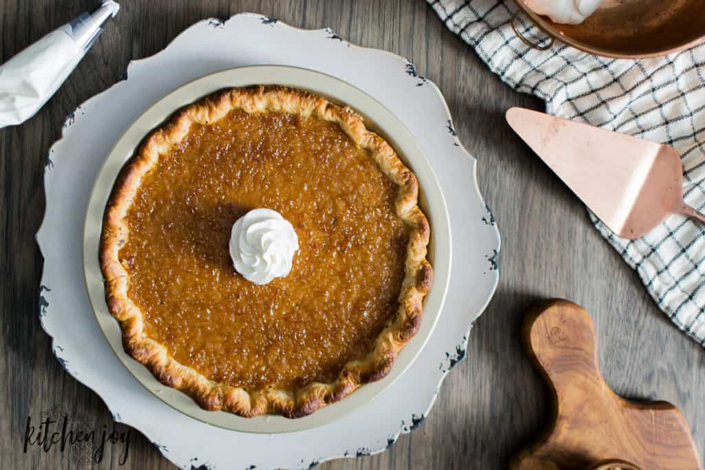 horizontal photo of whole maple bourbon pumpkin pie with crispy brulee top and a dollop of whipped cream