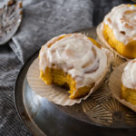 pumpkin sourdough cinnamon rolls with a bite out on a metal tray