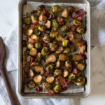roasted brussels sprouts and bacon with balsamic glaze on a large sheet pan