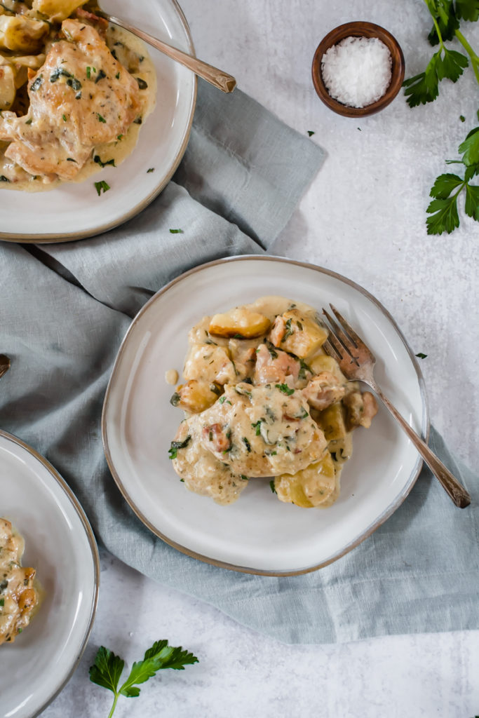 creamy dijon chicken thighs served on gray plates drizzled with sauce and chopped parsley