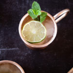 ginger gin mule cocktail served in frosty copper mug topped with lime wedge and sprigs of mint