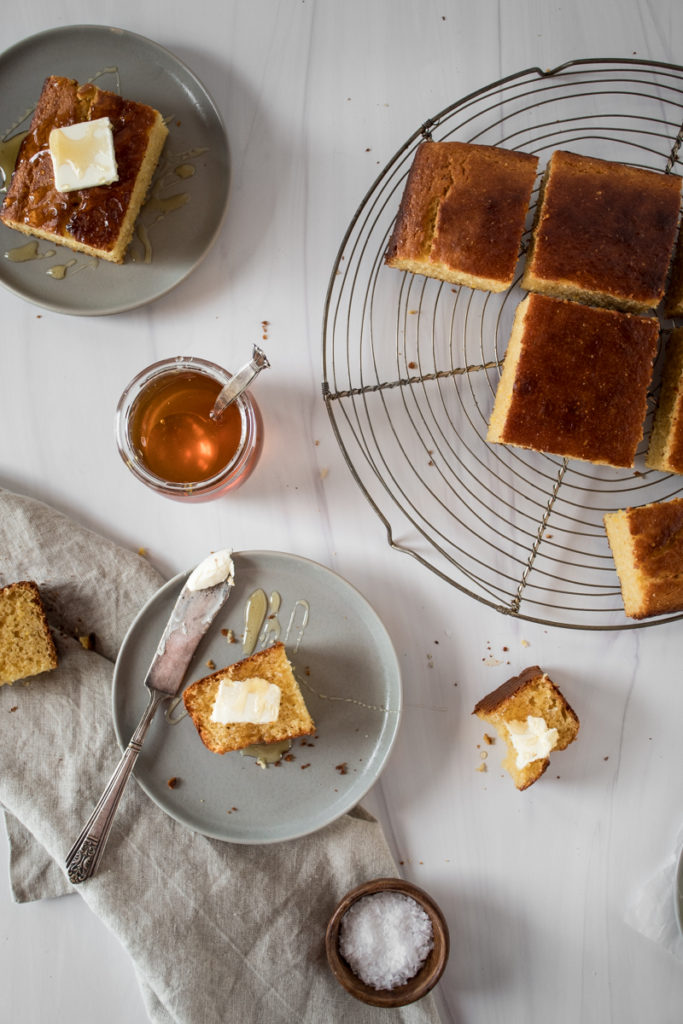 sweet honey cornbread cooling on a wire rack, cut into squares and served with creamy butter and drizzles of honey
