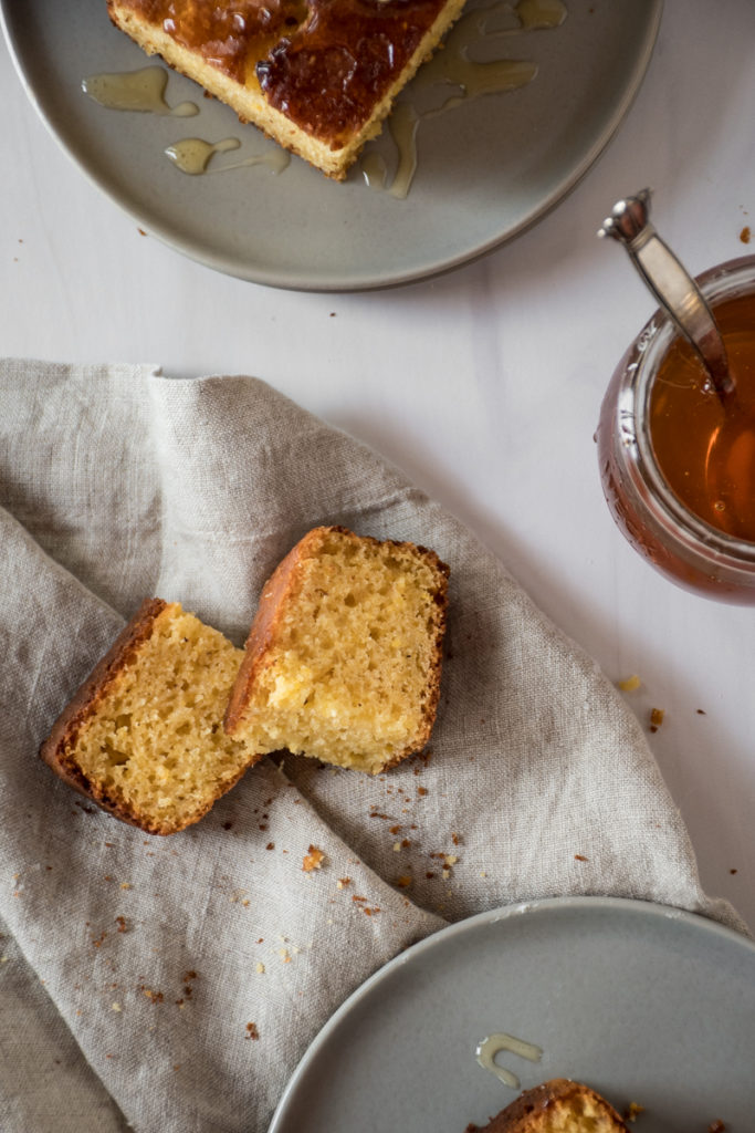 sweet honey cornbread cooling on a wire rack, cut into squares and served with creamy butter and drizzles of honey
