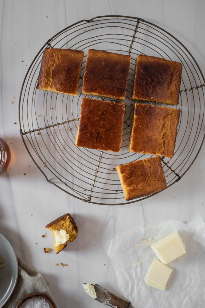 Sweet honey cornbread cut into squares, cooling on a wire rack, served with butter and honey