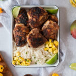 jamaican jerk chicken thighs smoked in an oven served with rice and mango salsa