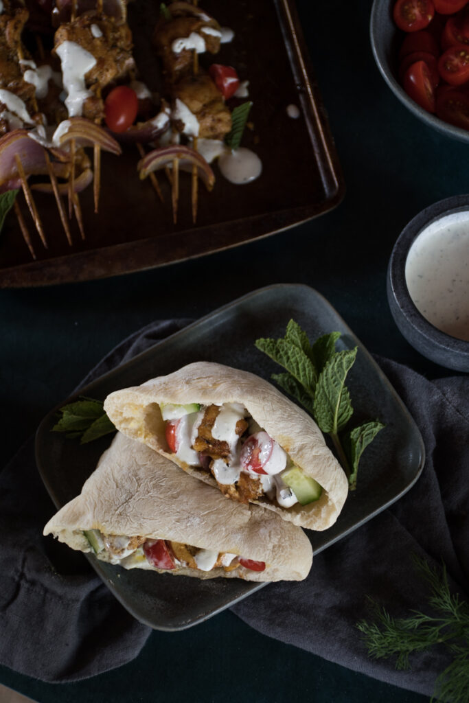 Grilled chicken shawarma served in a homemade pita drizzled with yogurt sauce and served with tomatoes and diced cucumbers