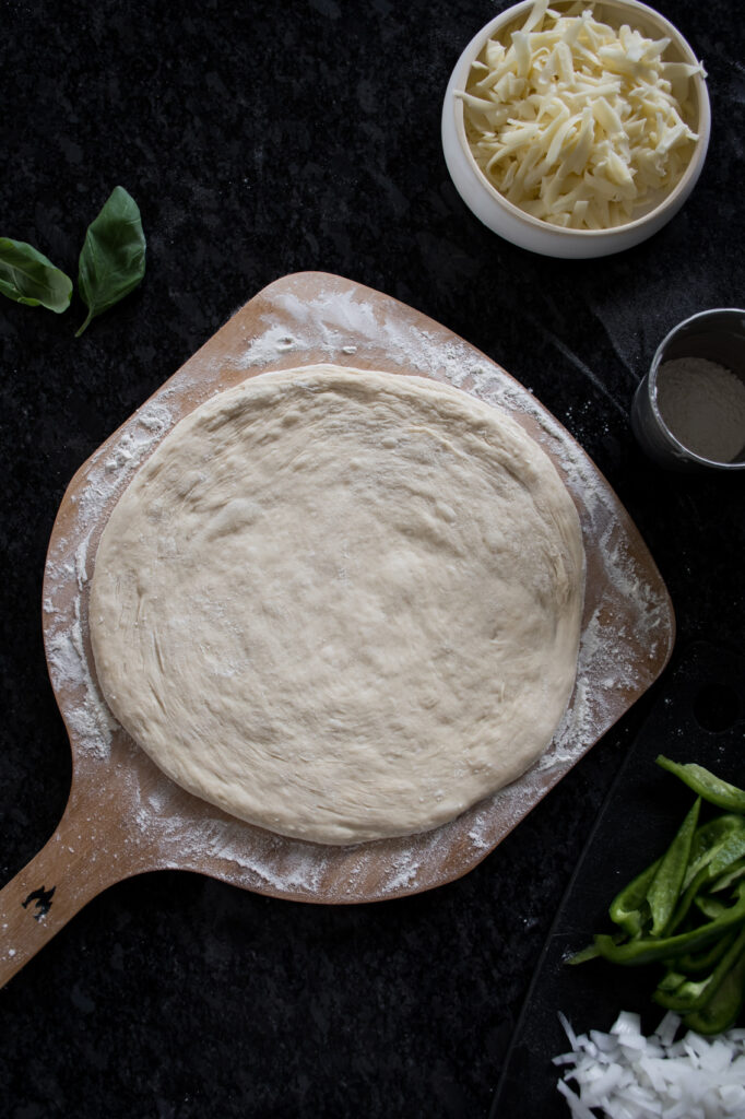 sourdough pizza dough stretched into a thin crust, ready to add toppings