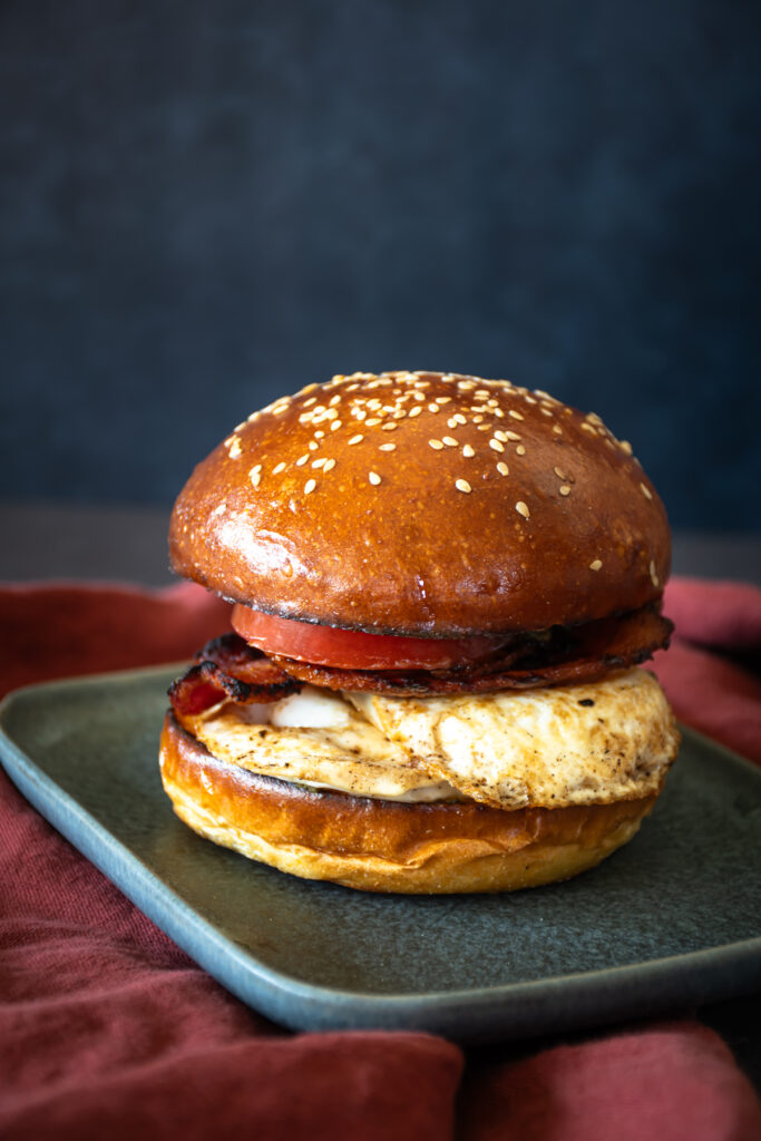 inspired by the Tartine Bakery breakfast sandwich, this sweet potato sourdough bun is toasted and filled with crispy bacon, an over easy egg, sliced fresh tomato, and a pesto aioli.